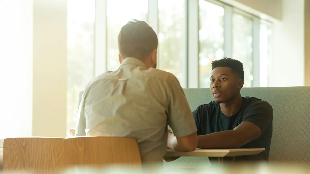 Persoon in gesprek met een ADHD-coach aan een tafel met een agenda en notities