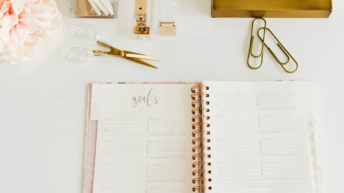 Student met agenda en laptop die een studieplanning opstelt aan een bureau