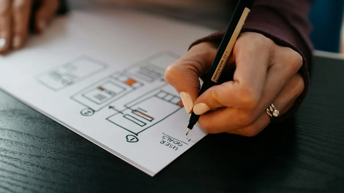 Vrouw aan een bureau met agenda en laptop, geconcentreerd bezig met plannen