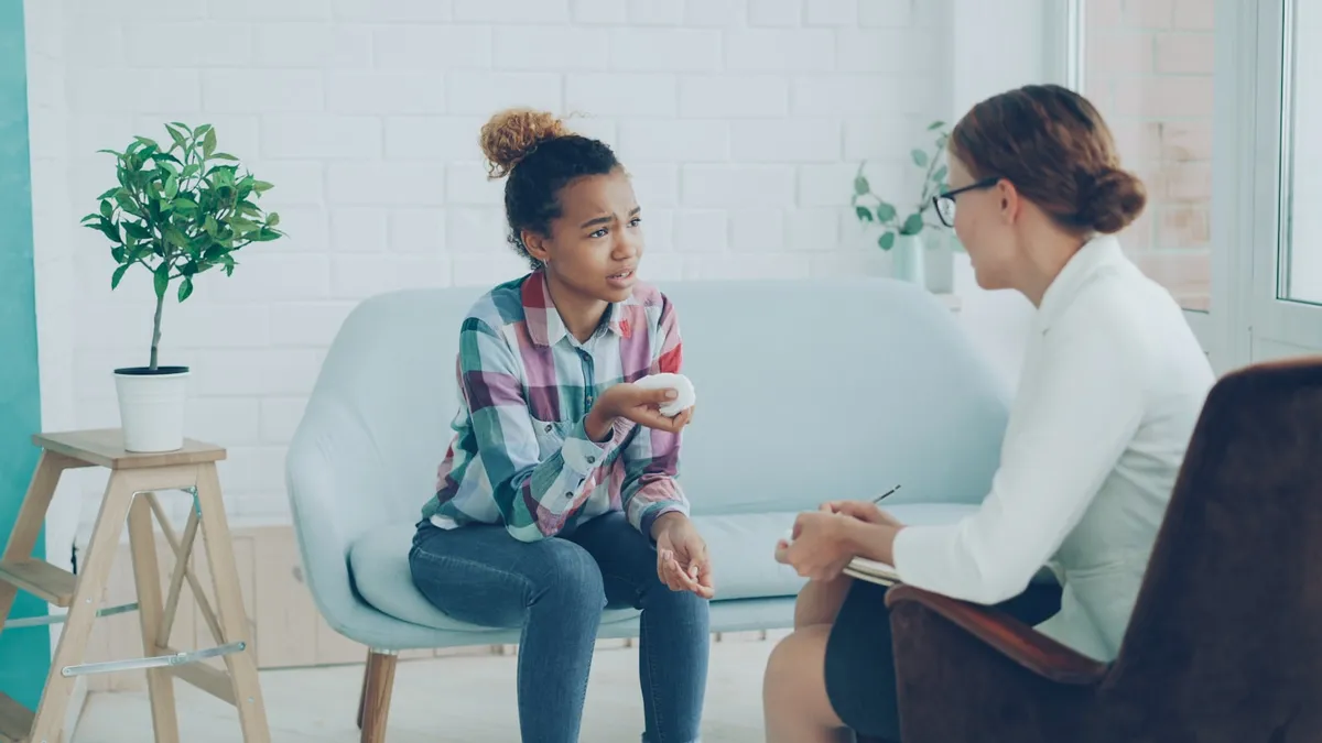 Volwassene in gesprek met een ADHD-coach naast een agenda en een pillendoosje op tafel