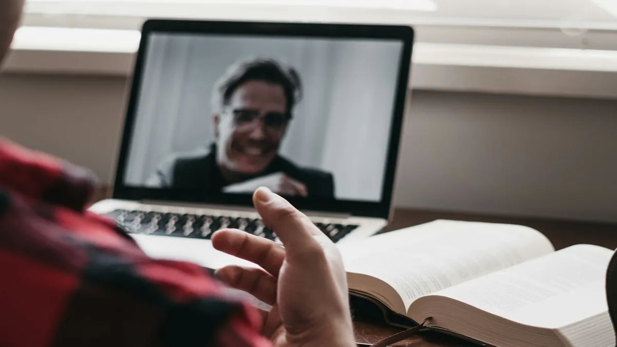 Volwassene met laptop tijdens een online coachinggesprek aan de keukentafel