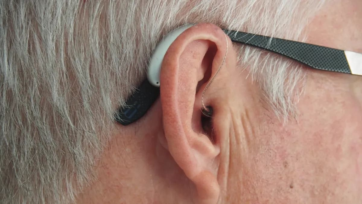 Persoon met koptelefoon doet een online hoortest op een smartphone aan de keukentafel