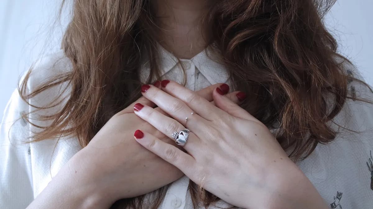 Persoon met de hand op de borst die twijfelt of hij hulp moet inschakelen bij pijn op de borst