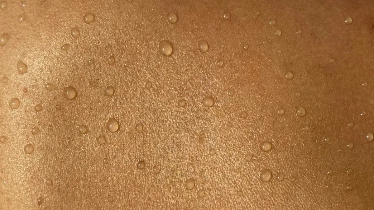 Persoon bekijkt een plekje op de huid van de arm bij daglicht in afwachting van een dermatologenafspraak