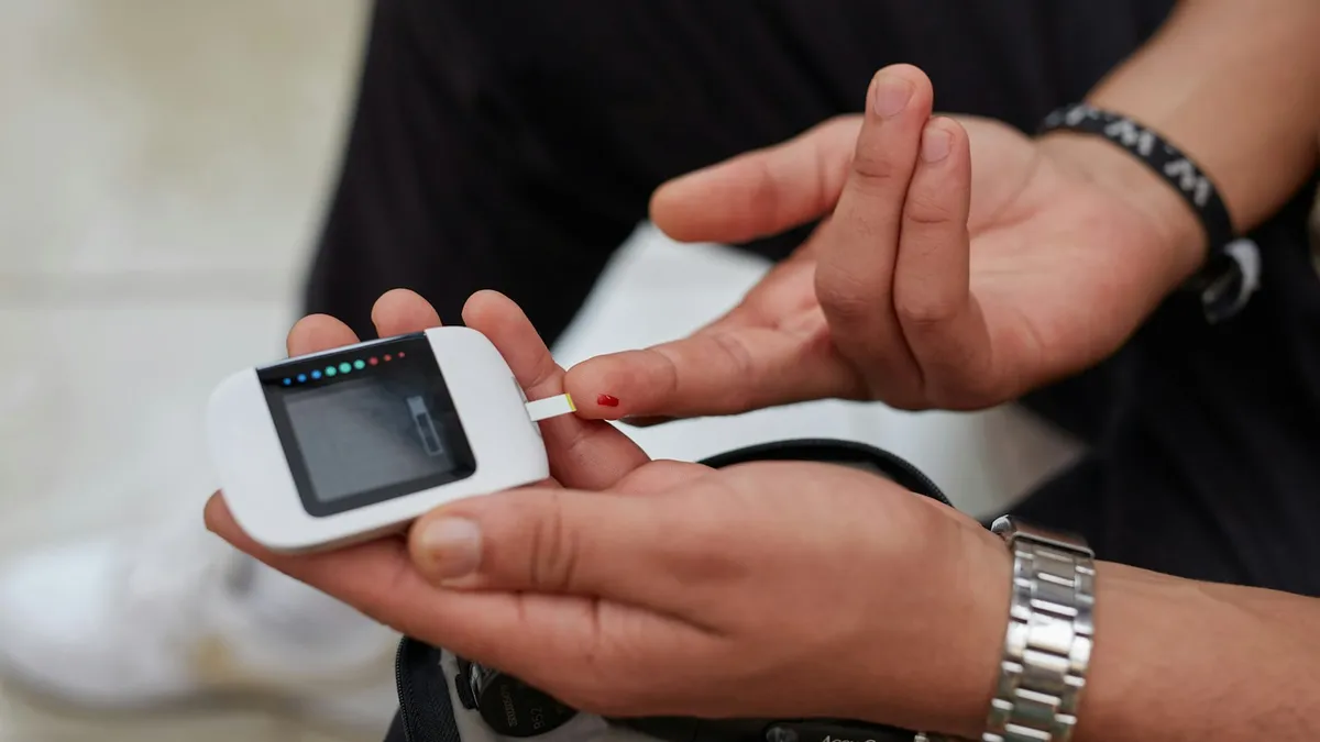 Persoon met diabetes type 1 die een glucosesensor op de arm afleest met een smartphone