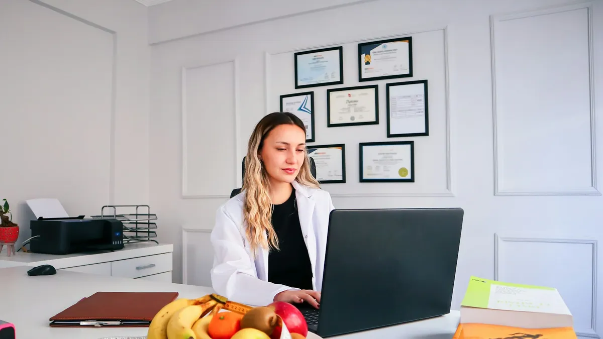 Persoon volgt een online gesprek met een diëtist aan de keukentafel