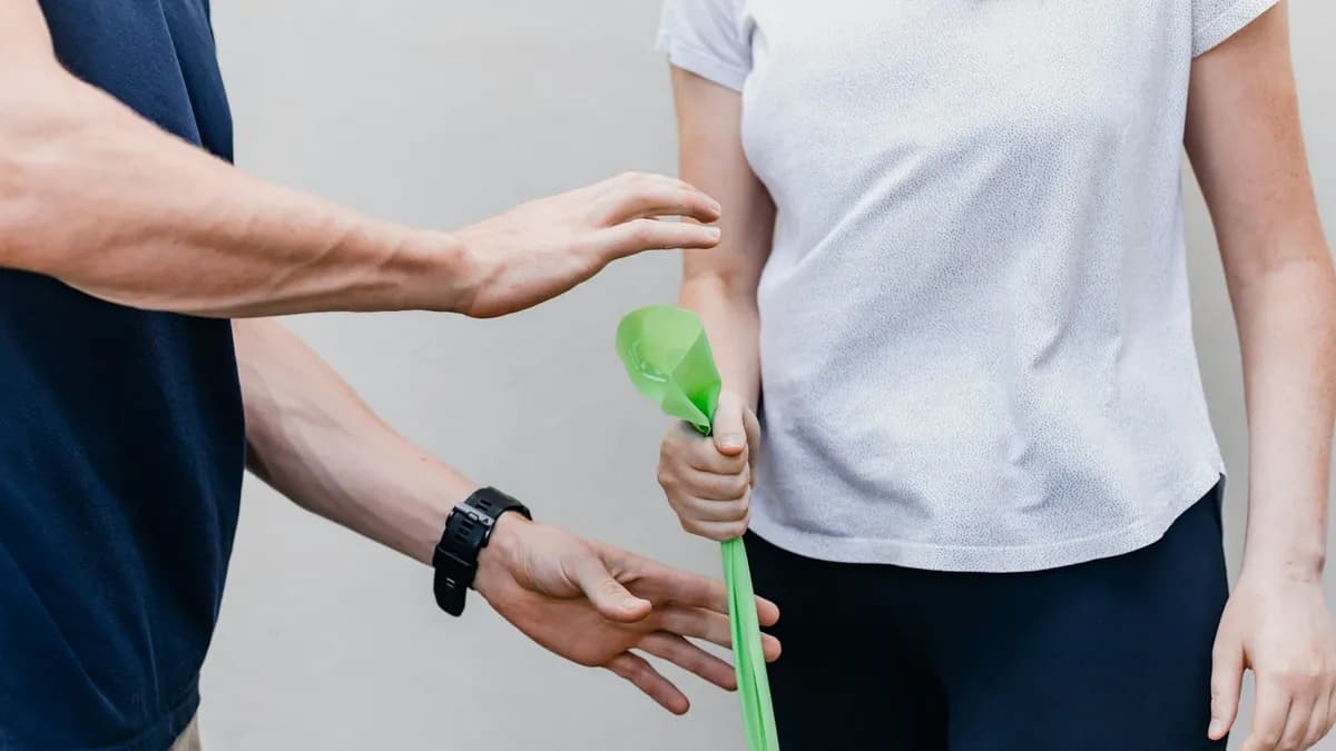 Kinesitherapeut bespreekt een oefenplan met een patiënt in een behandelruimte