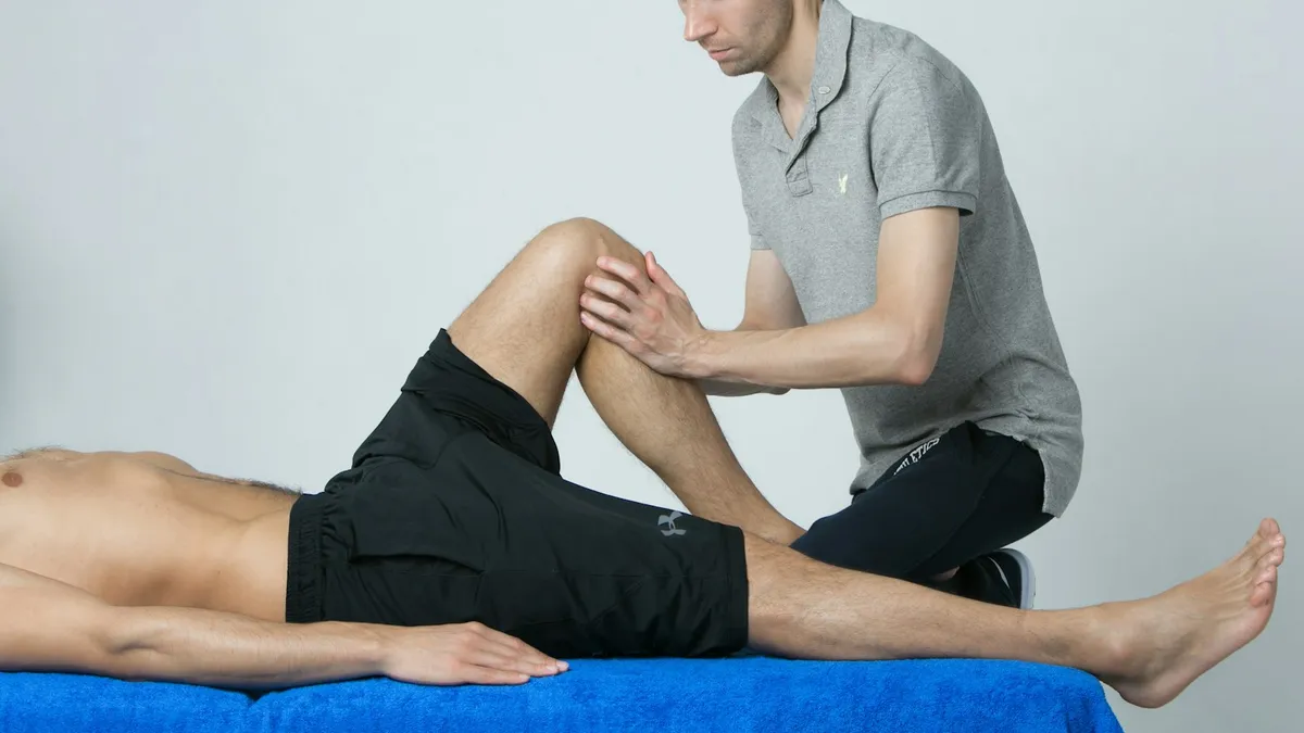 Kinesist begeleidt een patient bij een oefening in een kinepraktijk