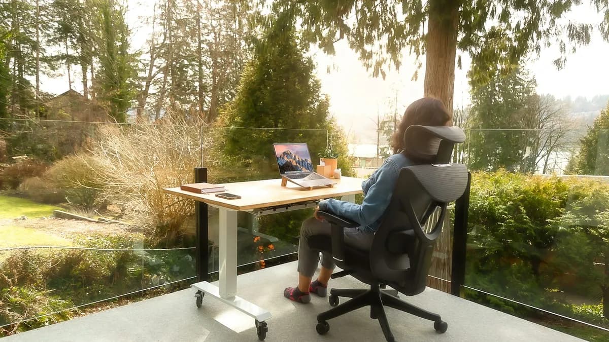 Persoon met nek- en schouderklachten aan een bureau achter een computerscherm