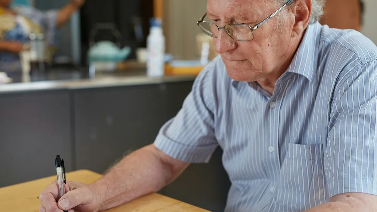 Oudere persoon en familielid bespreken kosten en documenten aan een tafel