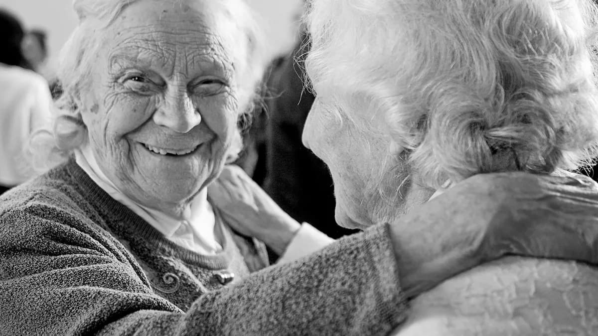 Oudere persoon bekijkt samen met een familielid notities aan de keukentafel