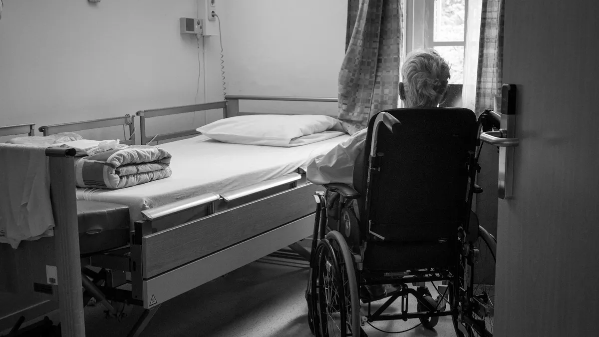 Huisarts en oudere patiënt bespreken zorgvragen aan een tafel