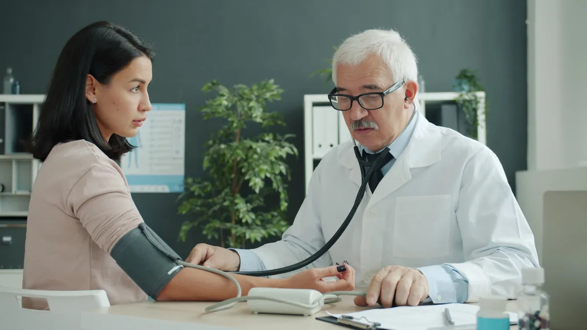 Mantelzorger zit naast oudere persoon tijdens een gesprek met een specialist
