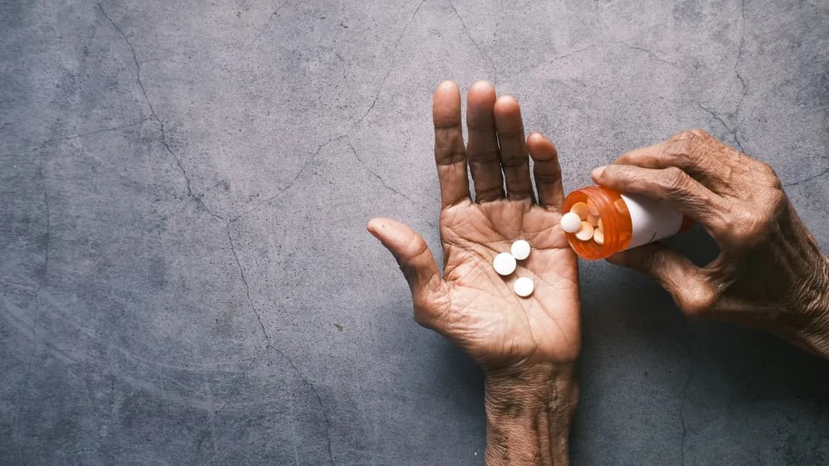 Volwassen dochter en oudere ouder overlopen samen de doosjes medicatie aan de keukentafel