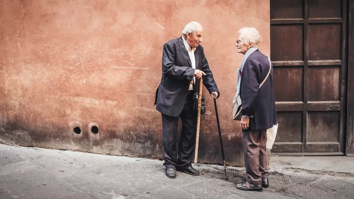Oudere persoon en begeleider wandelen samen rustig in een tuin