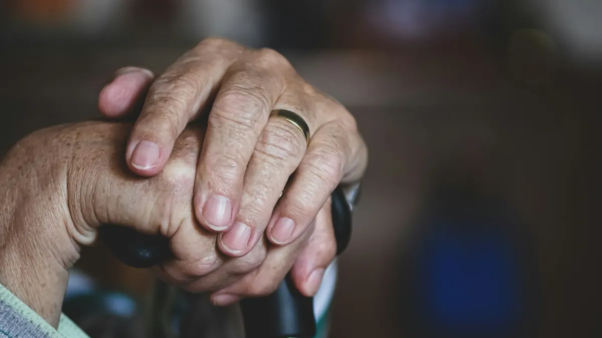 Geriatrische kinesitherapeut begeleidt een oudere persoon bij oefeningen thuis