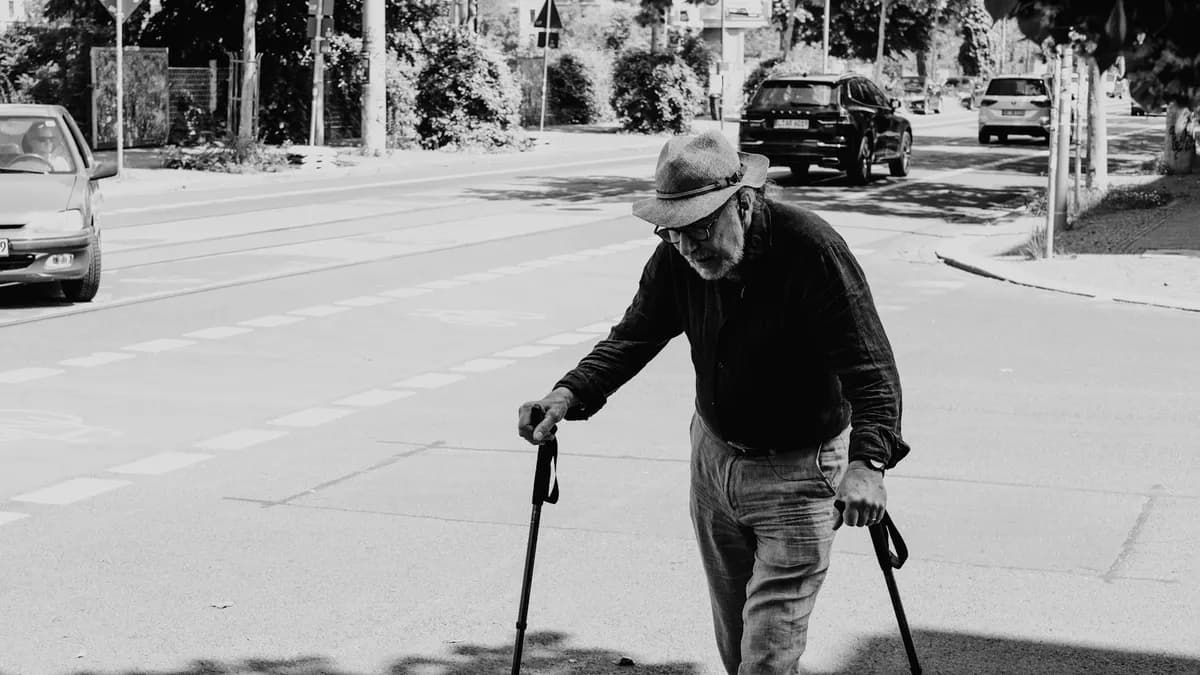 Oudere persoon wandelt buiten met een rollator en begeleiding