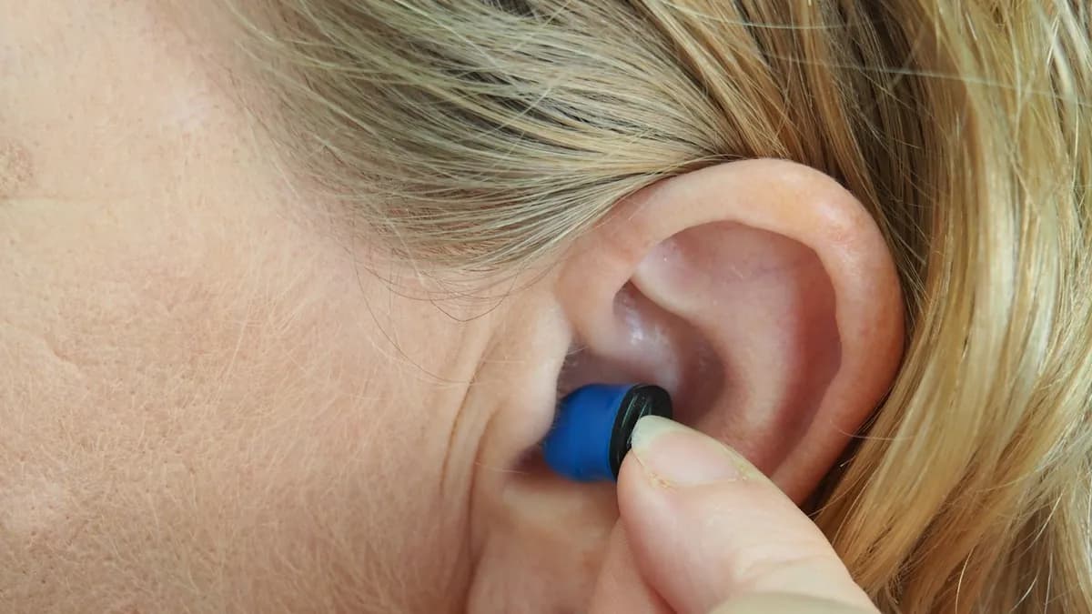 Persoon met hoorapparaat en smartphone die geluid bij tinnitus instelt