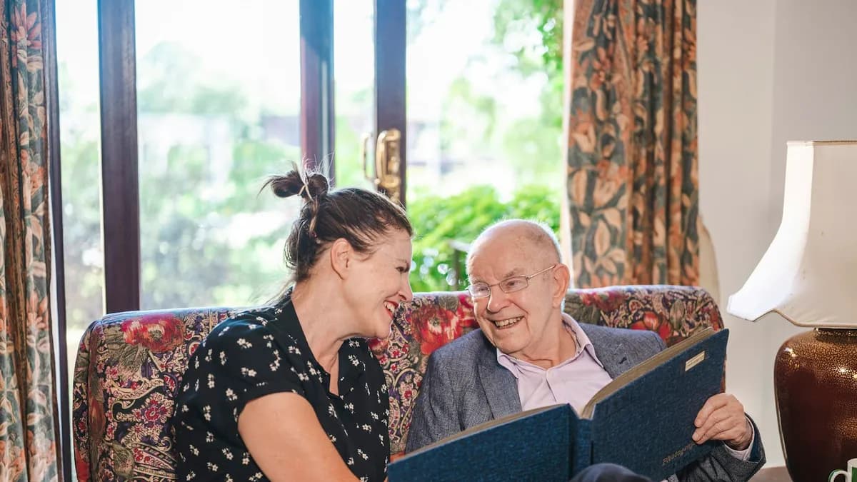 Thuiszorgmedewerker helpt een oudere persoon thuis in de woonkamer