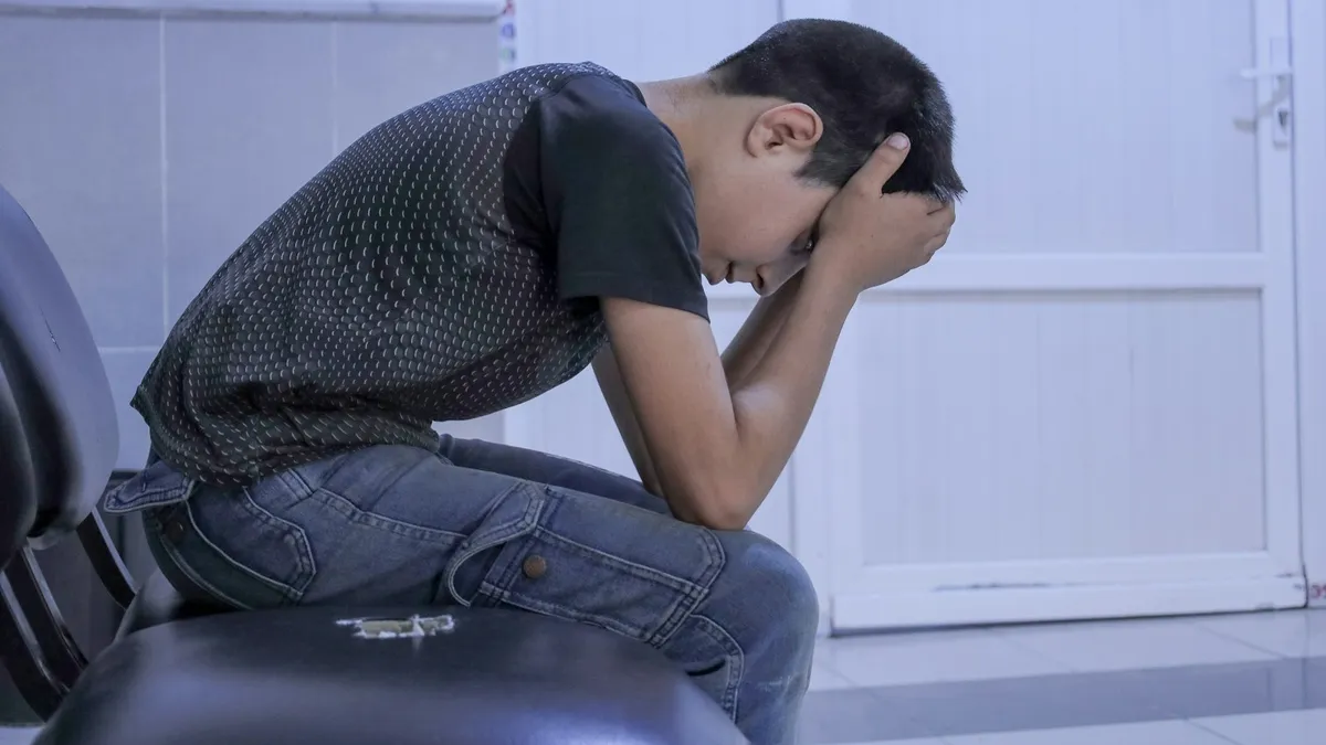 Kind kijkt bezorgd uit het raam terwijl een ouder geruststellend meeluistert