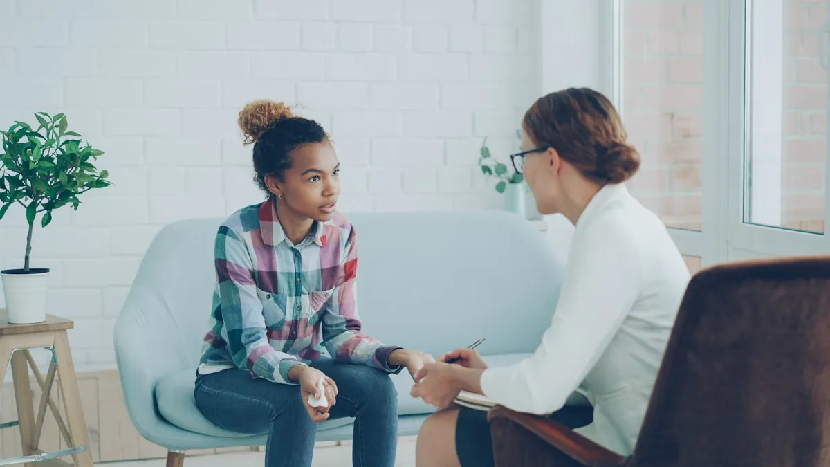 Persoon in gesprek met een complementair zorgverlener aan een tafel met een notitieboek