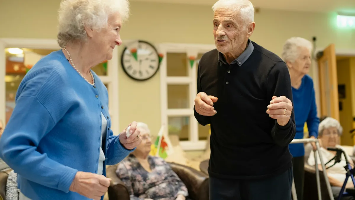 Oudere persoon met mantelzorger aan tafel tijdens een rustige maaltijd