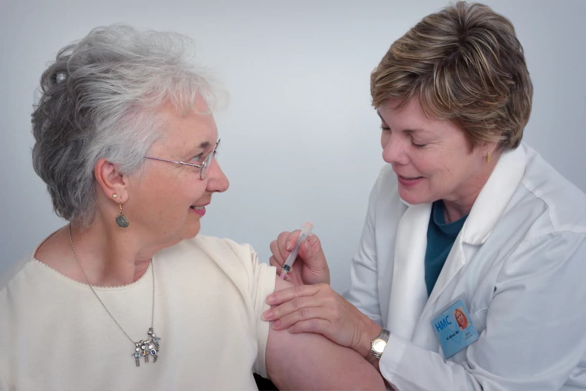 Persoon in herstel wandelt begeleid door een kinesitherapeut tijdens oncologische revalidatie