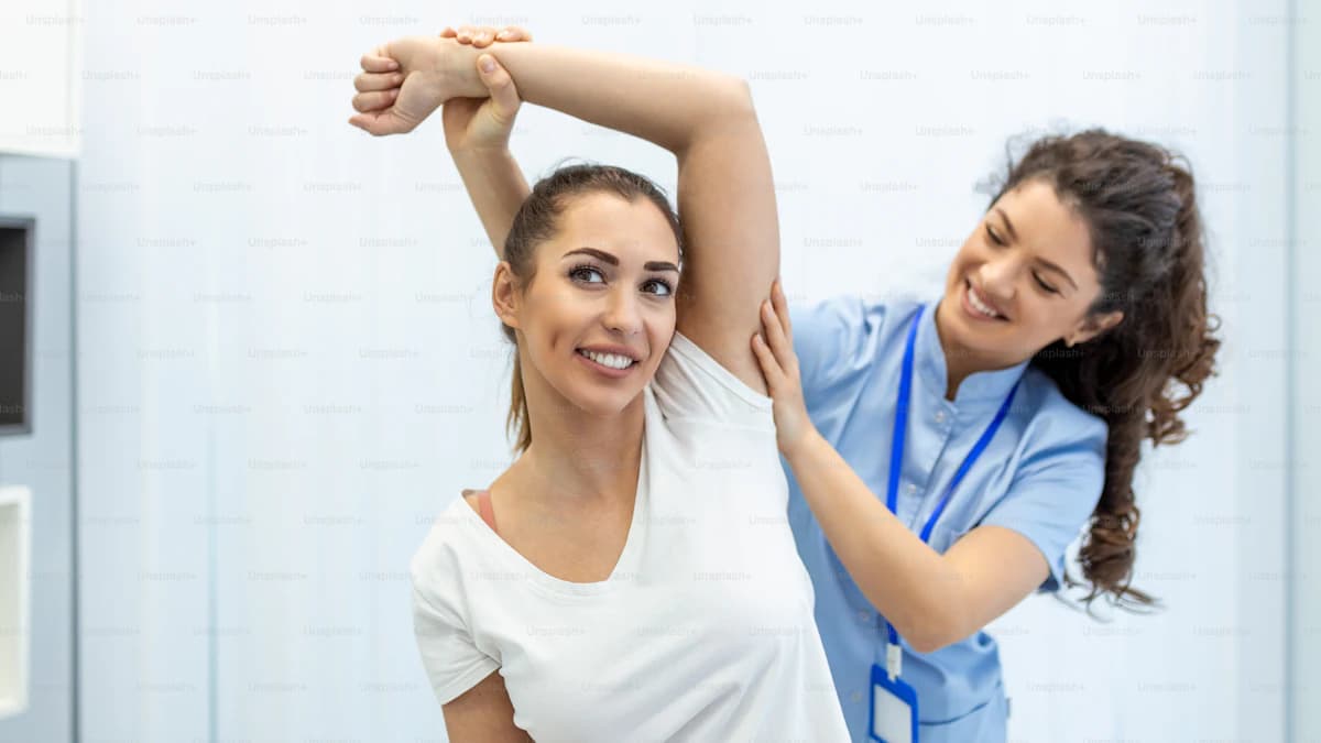 Kinesitherapeut begeleidt een persoon met armoefeningen bij lymfoedeem