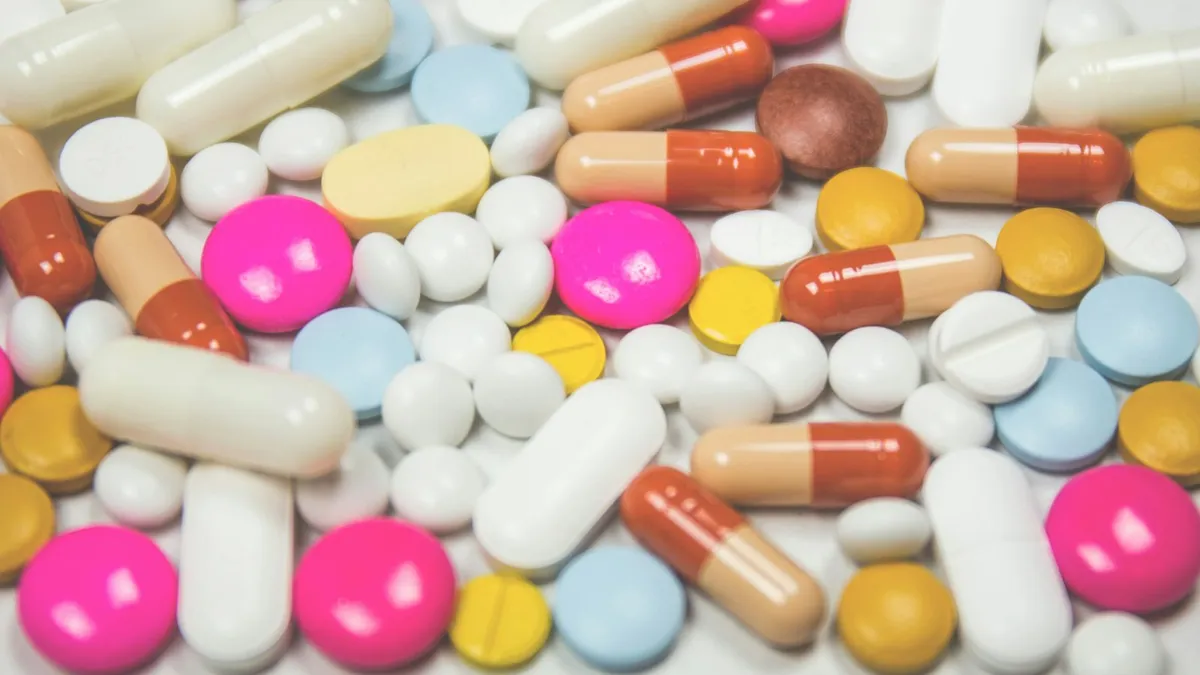 Persoon legt een lijst met medicatie en doosjes klaar op tafel voor een afspraak