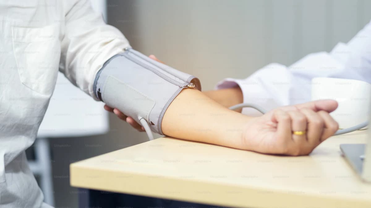 Plasmadonor rust in een donatiezetel terwijl een medewerker de bloeddruk opvolgt
