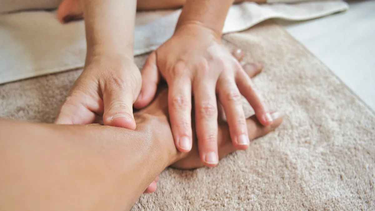Kinesitherapeut begeleidt een client bij een ontspannings- en ademhalingsoefening in de praktijk