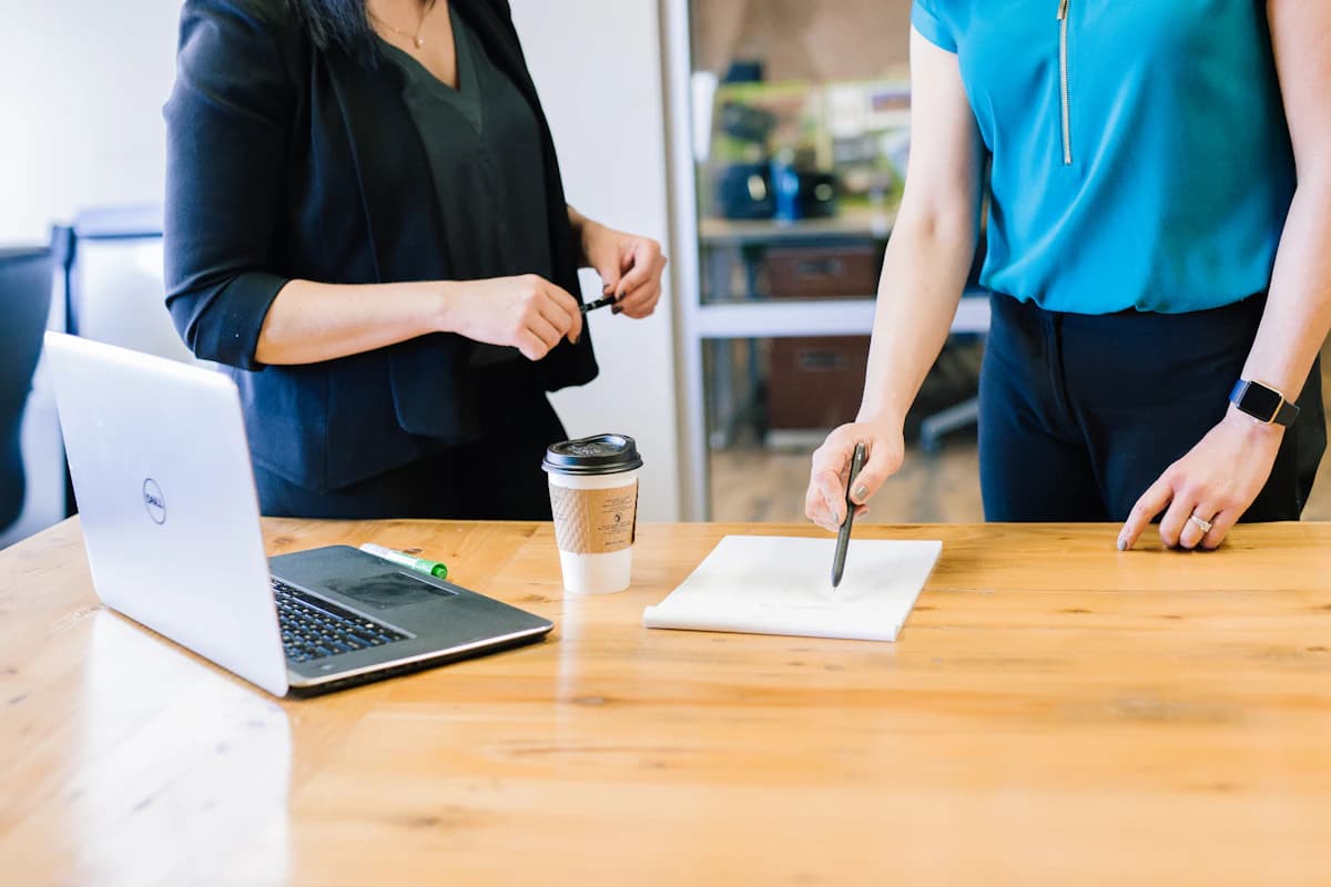 Vermoeide vrouw rust met de hand tegen het voorhoofd aan een tafel bij daglicht