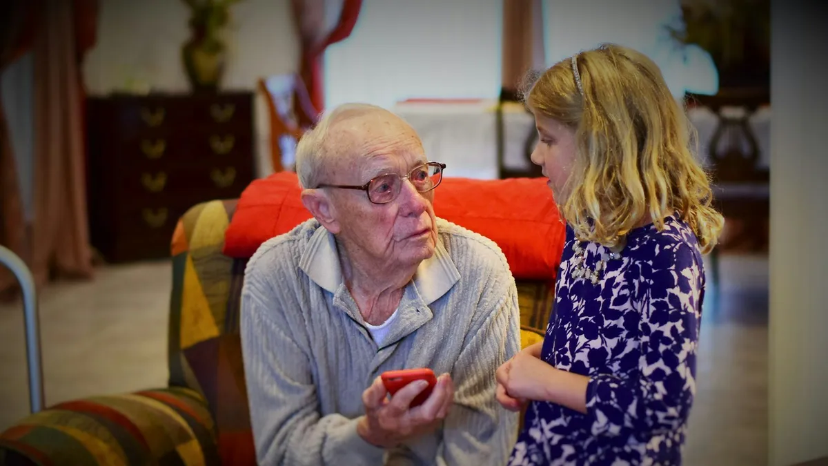 Volwassen kinderen in gesprek met hun oudere ouder aan de keukentafel
