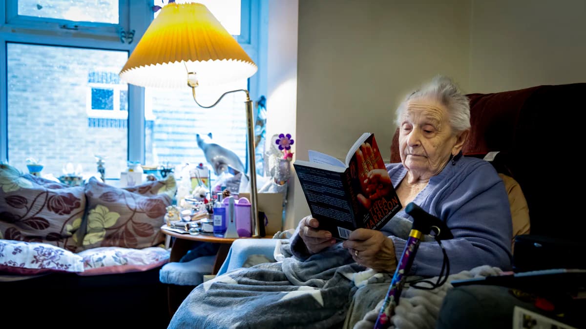 Thuisverpleegkundige die rustig overlegt met een oudere persoon in de woonkamer