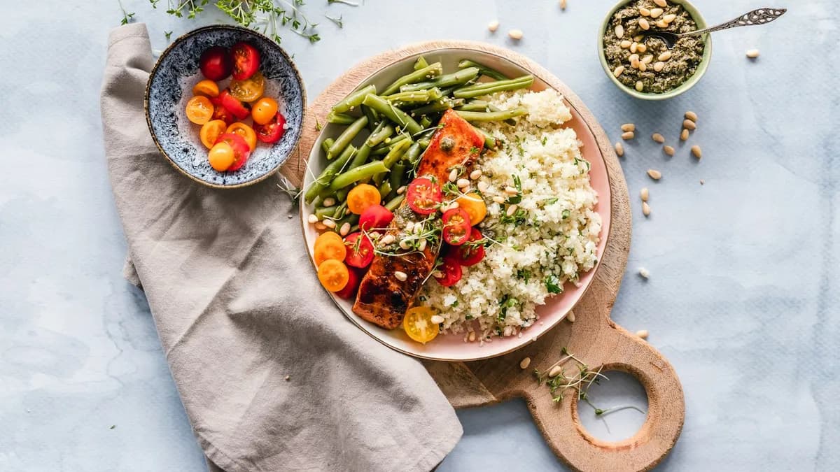 Persoon bereidt een gezonde maaltijd met verse groenten klaar aan de keukentafel