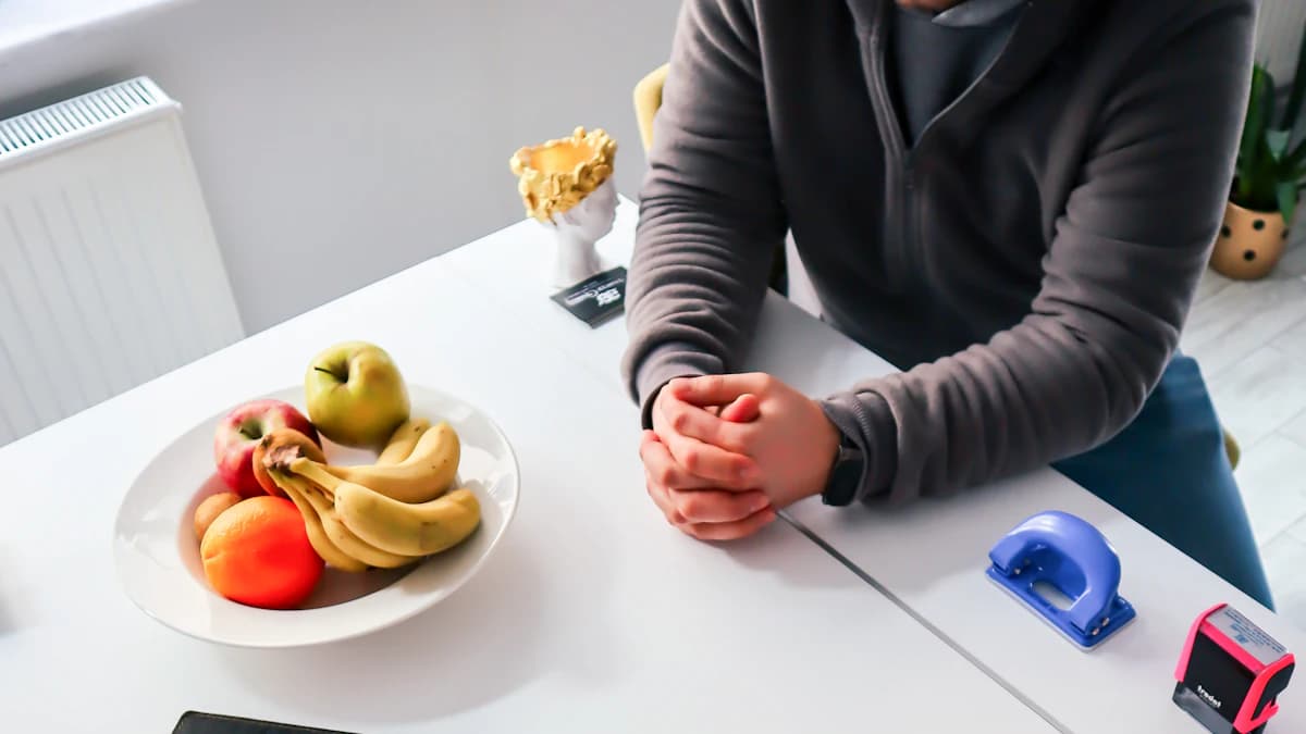 Persoon schrijft gevoelens en eetmomenten op in een voedingsdagboek aan de keukentafel